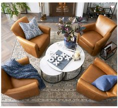 a living room with brown leather chairs and a white coffee table in front of a fireplace