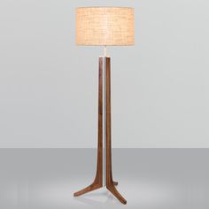 a wooden floor lamp with a beige shade