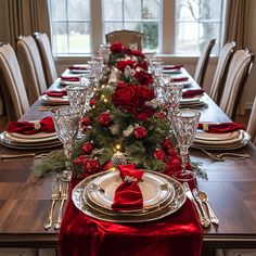 a table set for christmas dinner with red and white decorations, silverware and candlesticks