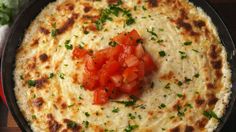 an omelet with tomatoes and parsley in a cast iron skillet on a wooden table