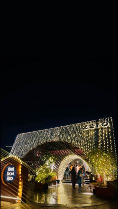 people are walking under an archway decorated with lights