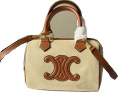 a white purse with brown handles and two initials on the front, sitting against a white background