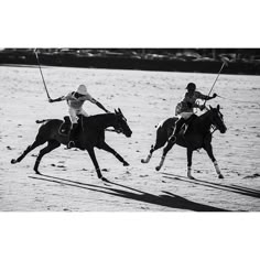 two men on horses are playing polo in the sand while another man is running behind them