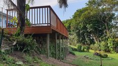 a wooden deck on the side of a house surrounded by trees