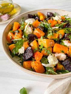 a salad with beets, carrots and feta cheese in a white bowl