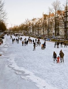 many people are walking in the snow near buildings