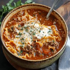 a bowl filled with pasta and meat sauce on top of a table next to a napkin