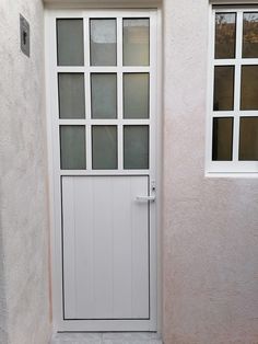 a white door and window on a house with stone flooring in front of it