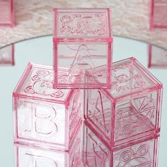 three pink glass blocks are stacked on top of each other in front of a circular table