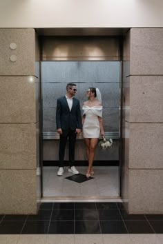 a man and woman standing next to each other in front of an open elevator door