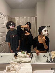 three people with painted faces are taking a selfie in the bathroom