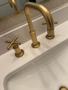 two gold faucets are sitting on the sink