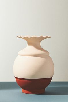 a white and red vase sitting on top of a blue table next to a wall