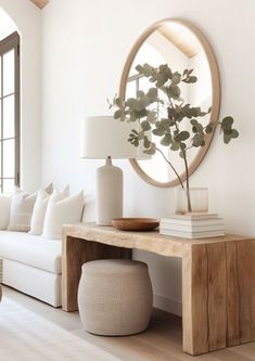 a living room filled with furniture and a large round mirror above the couch, on top of a wooden table