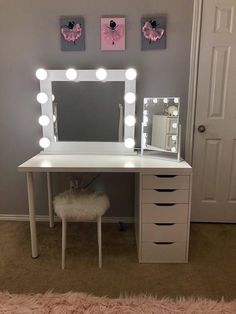 a white vanity with lights on it and a stool in front of the mirror that is lit up