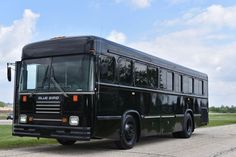 a black bus is parked on the side of the road in front of some grass