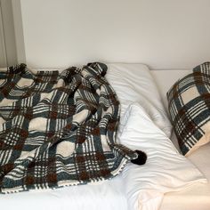 a bed with two pillows and a blanket on top of it next to a wall