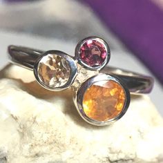 Genuine Multicolor Garnet .925 Ring Features Natural Red Garnet, Orange "Mandarin" Garnet & Golden Yellow "Imperial" Garnet In A Nontraditional Trilogy Design In .925 Sterling Silver. Ethically Sourced Gems In A Limited Edition Item Imported From The Uk. Bundle 2+ Items For Best Deal. I Have A Wide Selection Of Fine Jewelry As Well As Gemstone Candles, Art Prints, Clothing & More. I'm A Certified Gemologist & Gia Ajp So Shop With Confidence! Round Sterling Silver Gemstones Fine Jewelry, Fine Sterling Silver Gemstones, Silver Gemstones With Bezel Setting For Anniversary, Multicolor Sterling Silver Fine Jewelry Gemstones, Multi-stone Citrine Gemstone Ring, Fine Jewelry Silver Gemstones With Bezel Setting, Multi-stone Citrine Gemstones, Anniversary Citrine Birthstone Gemstones, Sterling Silver Multi-stone Ruby Ring