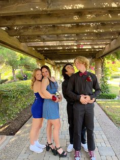 three people are posing for a photo under a covered area with flowers and greenery