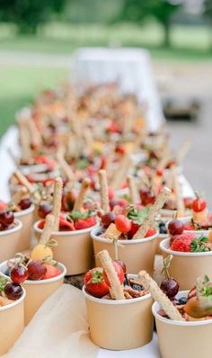 many small cups filled with food on top of a white table covered in fruit and veggies