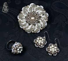 three pieces of jewelry sitting on top of a black cloth covered table next to each other