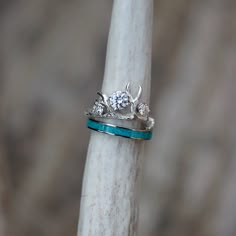 a close up of a ring on top of a white piece of wood with two diamonds