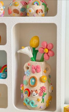 there is a vase with flowers in it on the shelf next to other toys and decorations