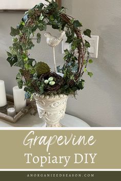 a white vase filled with greenery and eggs on top of a table next to candles