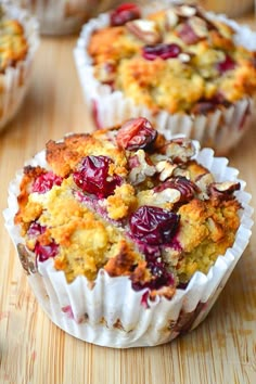 several muffins with cranberries and nuts in them on a wooden table