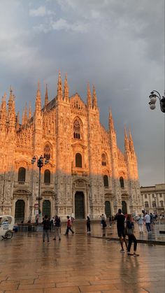 people are walking around in front of a cathedral