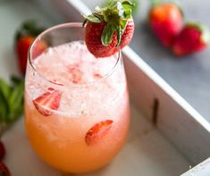 a close up of a drink in a glass on a tray with strawberries around it