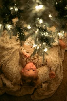 a baby is laying under the christmas tree