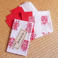 four red and white napkins sitting on top of a wooden table next to each other