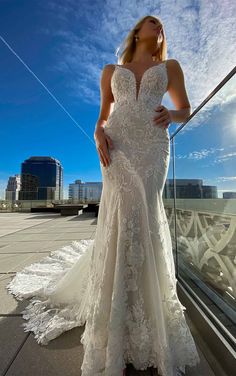 a woman in a wedding dress standing on a balcony with her hands on her hips