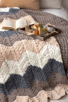 a blanket that has some food on top of it next to an open book and cup