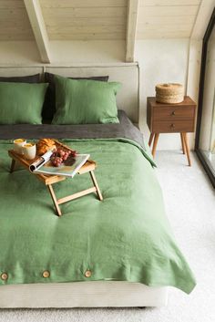 a tray with food sitting on top of a bed in a bedroom next to a window