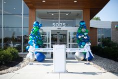 an entrance to a building decorated with blue and green balloons, streamers and ribbons