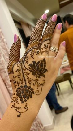 a woman's hand with henna tattoos on it, and her hands in the background