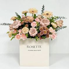 a white vase filled with lots of pink and yellow flowers