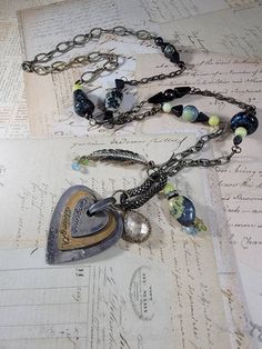 "Art Assemblage Necklace: I created the long necklace by building it around a Mixed Metal heart that says \"gorgeous strength, and spirit\" with some odd charms from salvaged jewelry.  There are stone and Czech glass beads, and brass feather charms, chips, chrystal charm and patinaed brass chains. The eclectic mix is very organic, natural and endearing. It measures 33 inches long with a 4 inch pendant that is adjustable with a lobster clasp." Heart-shaped Sterling Silver Soldered Necklace, Sterling Silver Heart-shaped Soldered Necklaces, Sterling Silver Heart-shaped Soldered Necklace, Sterling Silver Heart Necklace With Soldered Details, Metal Heart Pendant Necklace With Soldered Details, Unique Metal Jewelry With Heart Charm, Heart-shaped Metal Necklace With Soldered Details, Unique Metal Necklace With Heart Charm, Bohemian Heart-shaped Metal Charm Necklace