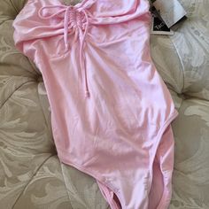 a pink one piece swimsuit laying on top of a couch