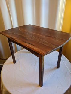 a wooden table sitting on top of a white cloth