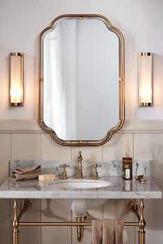 a bathroom sink with a mirror above it and two lights on the wall behind it