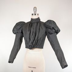 "An adorable mid-1890s bodice with the cutest bows in the back and wonderful gigot or leg of mutton sleeves. Hook and eye closures up the front hidden beneath another fabric panel. There is a small hidden pocket watch pocket beneath the front panel. Hooks inside the bodice to attach a skirt. This piece has quite a bit of hand sewn details! One boning channel down the center back of the lining. There is a subtle pattern to the fabric, which is a very soft cotton or cotton blend. I believe this wo Victorian Shirt, Gigot Sleeve, 1890s Fashion, Leg Of Mutton Sleeve, Watch Pocket, Victorian Clothing, Fabric Panel, Hidden Pocket