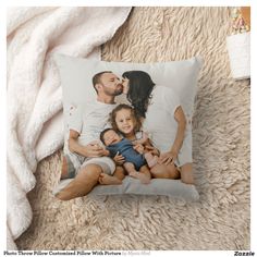 a pillow with a family photo on it sitting on a fluffy white carpet next to a blanket