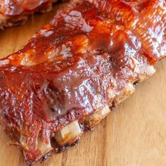 ribs covered in bbq sauce sitting on top of a wooden cutting board