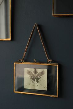 two framed pictures hang on the wall next to each other with rope hanging from them