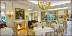 a dining room with tables, chairs and a fire place in the middle of it