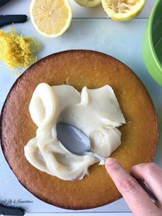 someone is spreading icing onto a cake with lemons and other ingredients around it