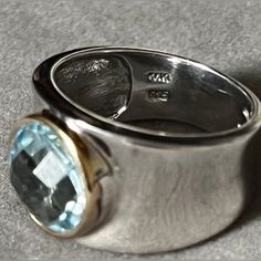 Rare Find Self For $135.00 On Etsy Sterling Silver And 14k Gold Faceted Blue Topaz Ring Vintageblinget Item Details @ Vintage K. Size: 7 Us 4 Materials: Gold, Silver, Stone Gemstone: Topaz %. Gem Color: Blue Band Color: Silver This Ring Features A Wide Band With Faceted Round Blue Topaz Ring Bezel Set In A Gold Frame At Its Center. The Band Is Approximately 10mm In The Front And 4mm In The Back. It Is Marked 925 And 14k Thailand On The Inside Of The Band. This Ring Is A Size 7 And Is In Wonderful Preloved Condition. Please See All Photos For Details And Condition. Modern Topaz Ring With Gemstone Accents For Formal Occasions, Modern Topaz Ring With Gemstone Accents, Luxury Blue Topaz Ring With Polished Finish, Luxury Polished Blue Topaz Ring, Luxury Topaz Ring With Bezel Setting Gift, Formal Blue Topaz Ring With Bezel Setting, Modern Topaz Ring With Gemstone Accents For Anniversary, Luxury Hallmarked Blue Topaz Ring, Luxury Blue Topaz Diamond Ring